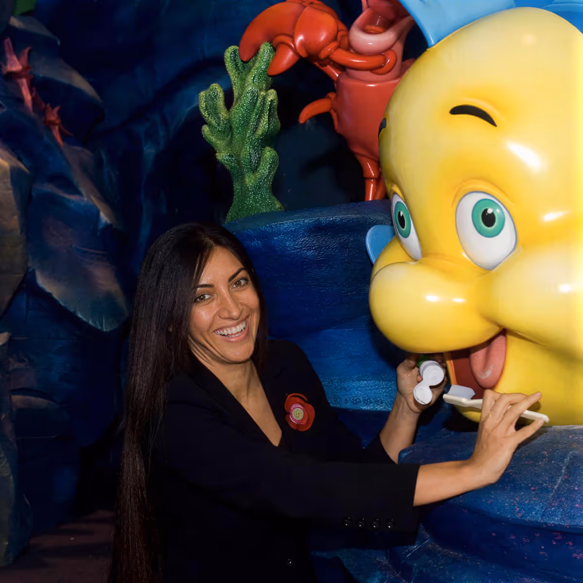 Dr. Afsoon Elmore, pediatric dentist, brushing a giant cartoon fish's teeth